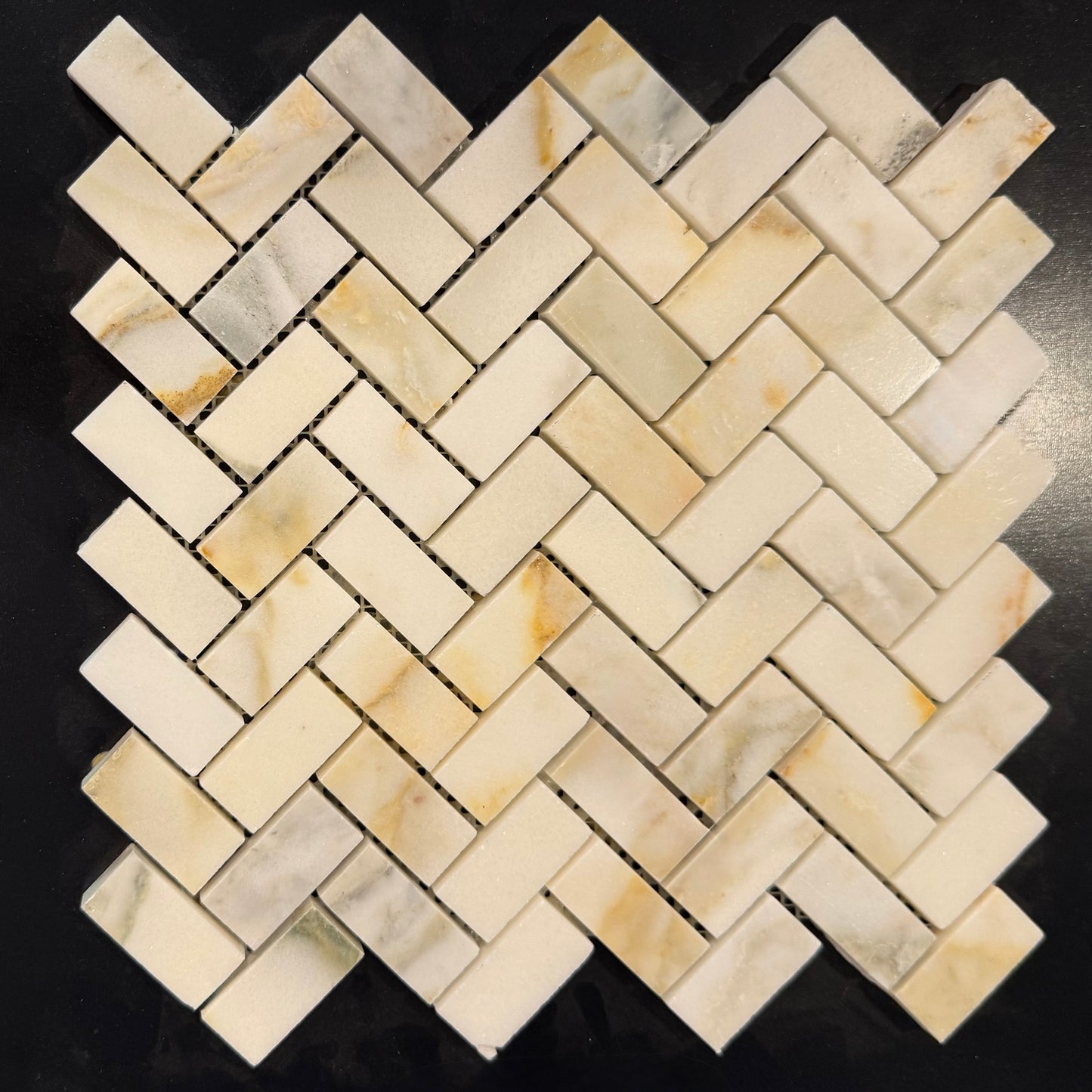 Beige herringbone mosaic tile pattern on a black background