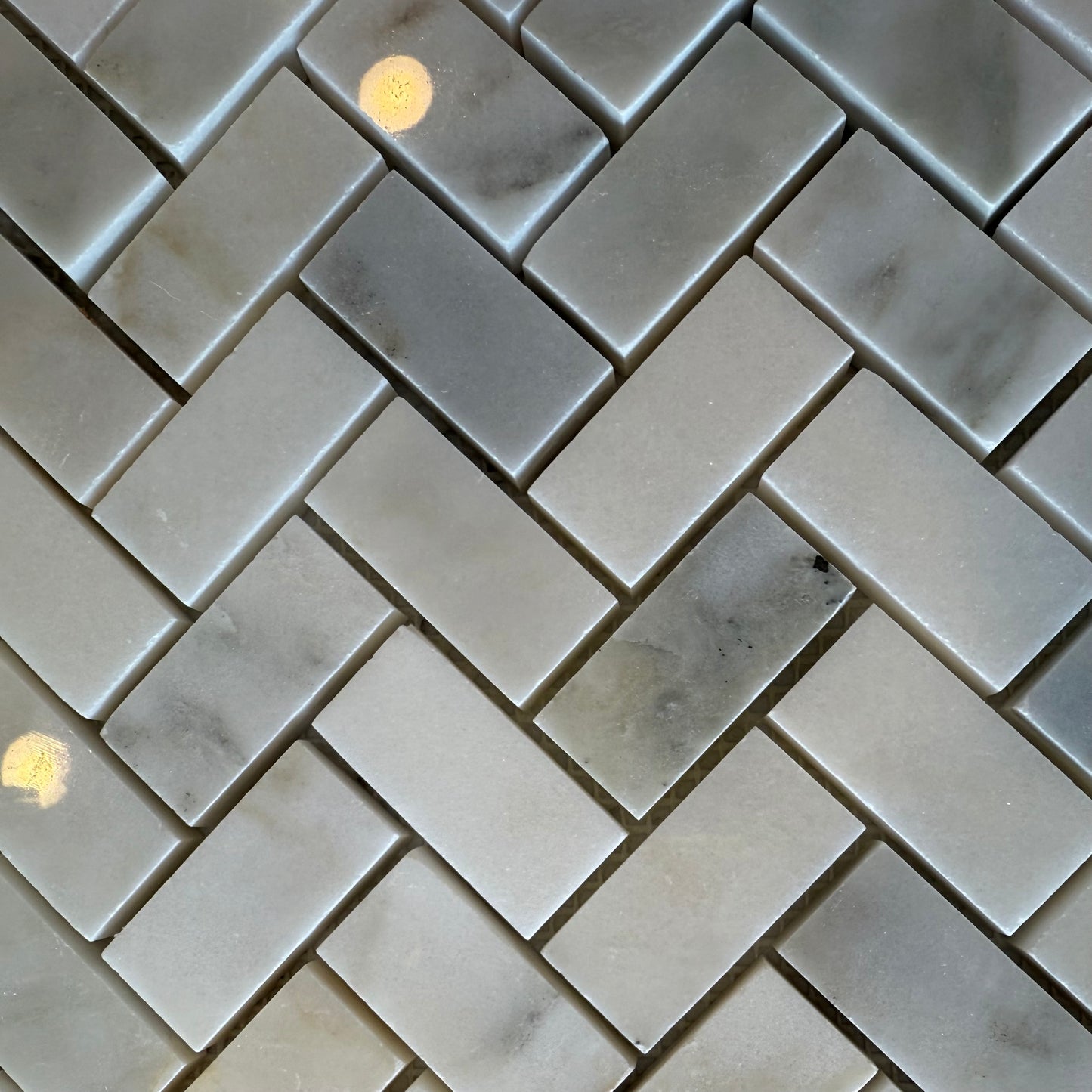Gray marble tiles arranged in a herringbone pattern