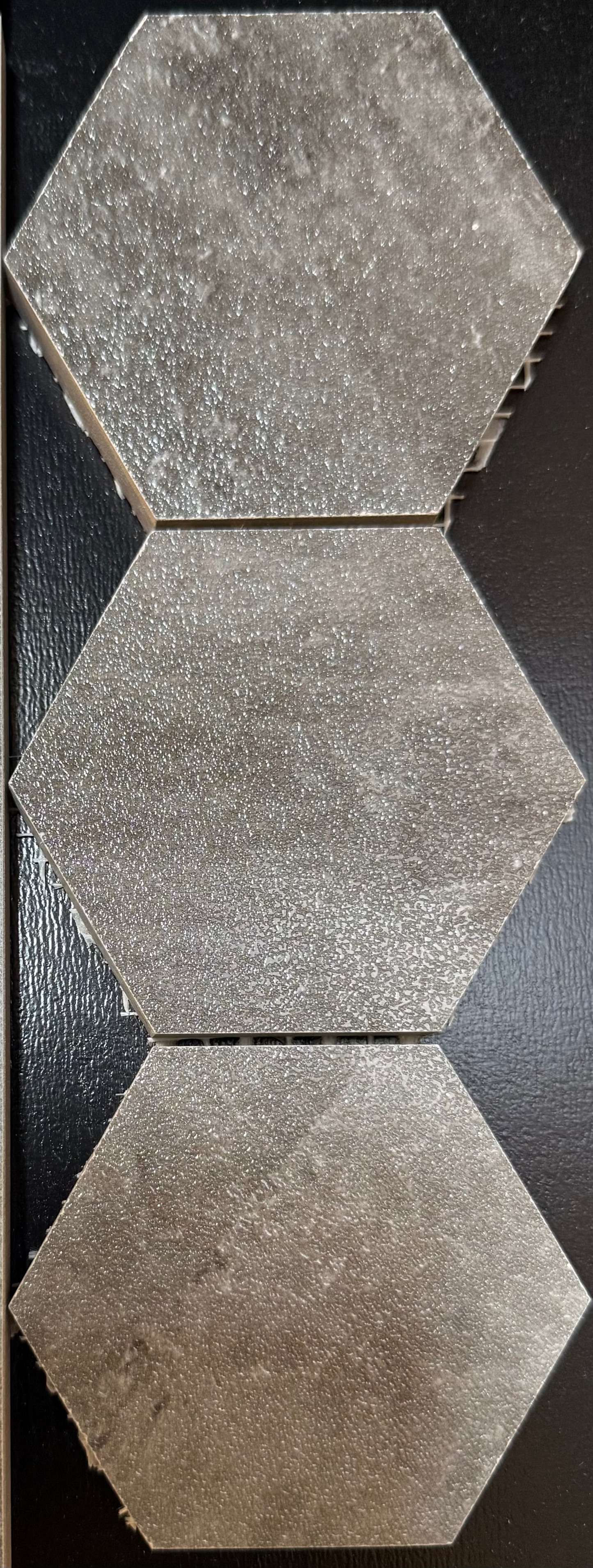 Three hexagonal tiles with a textured surface on a dark background