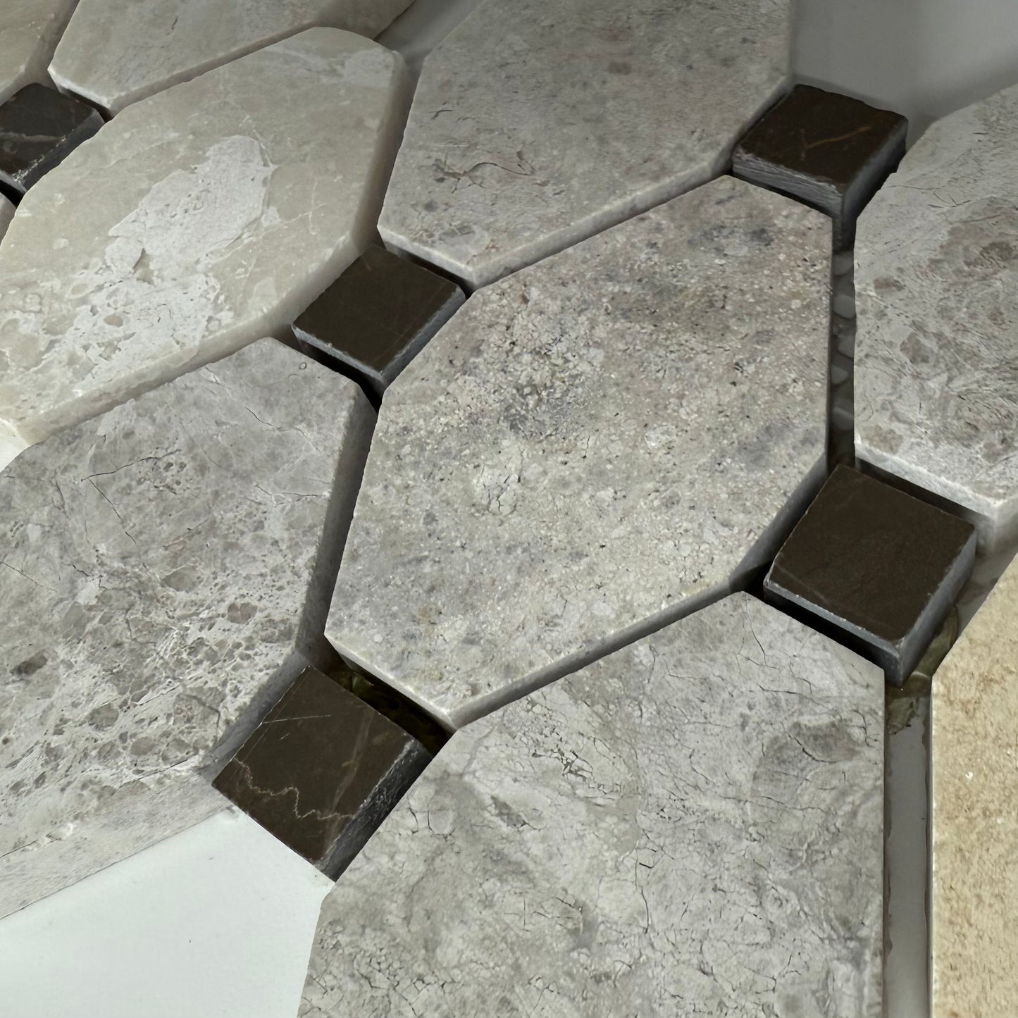 Hexagonal stone tiles with a mix of gray and brown colors on a tiled floor.