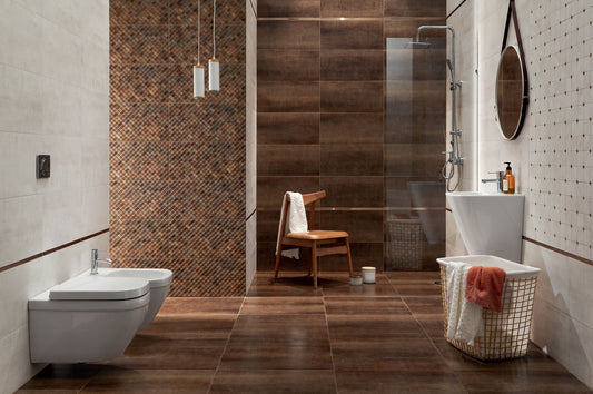 A modern bathroom interior with dark brown wood-look floor and wall tiles, a white wall-mounted toilet, a white pedestal sink, a glass shower enclosure, and a small wooden chair with a towel draped over it.