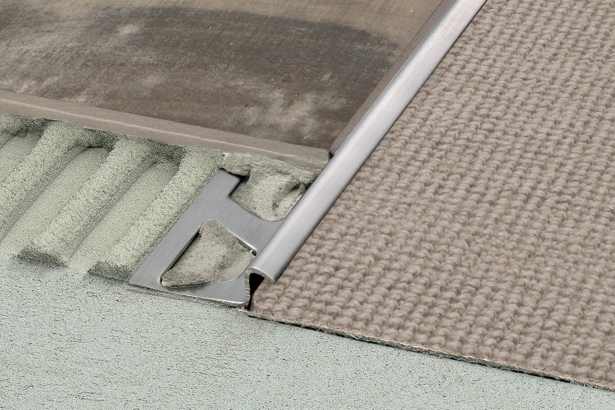 Close-up of a metal threshold between two different flooring materials.
