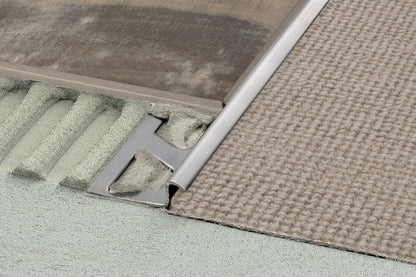 Close-up of a metal threshold between two different flooring materials.