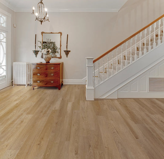 Antique oak wood flooring installed in a home, featuring a staircase and a living room with a wooden dresser and a mirror.