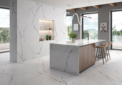 A modern kitchen island with a white and gray marble-look countertop and base, paired with light wood side panels and three bar stools, set in a bright contemporary kitchen with large windows.
