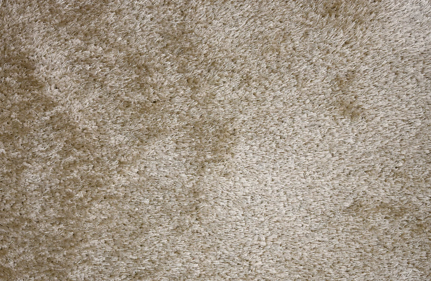 A close-up texture shot of a shaggy, high-pile carpet in a warm beige or taupe color.
