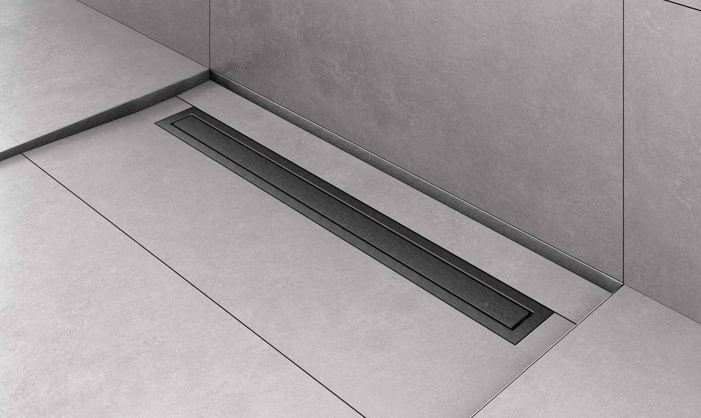 A long, low-profile linear floor drain set into a light gray tiled bathroom floor and wall.