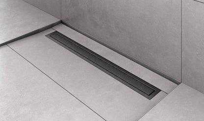 A long, low-profile linear floor drain set into a light gray tiled bathroom floor and wall.