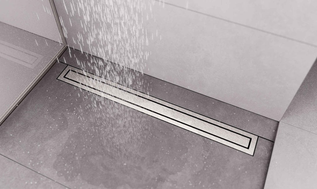 A linear floor drain installed in a tiled shower area, shown with water spraying over it.
