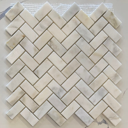 Marble mosaic tile sample in a herringbone pattern on a white background