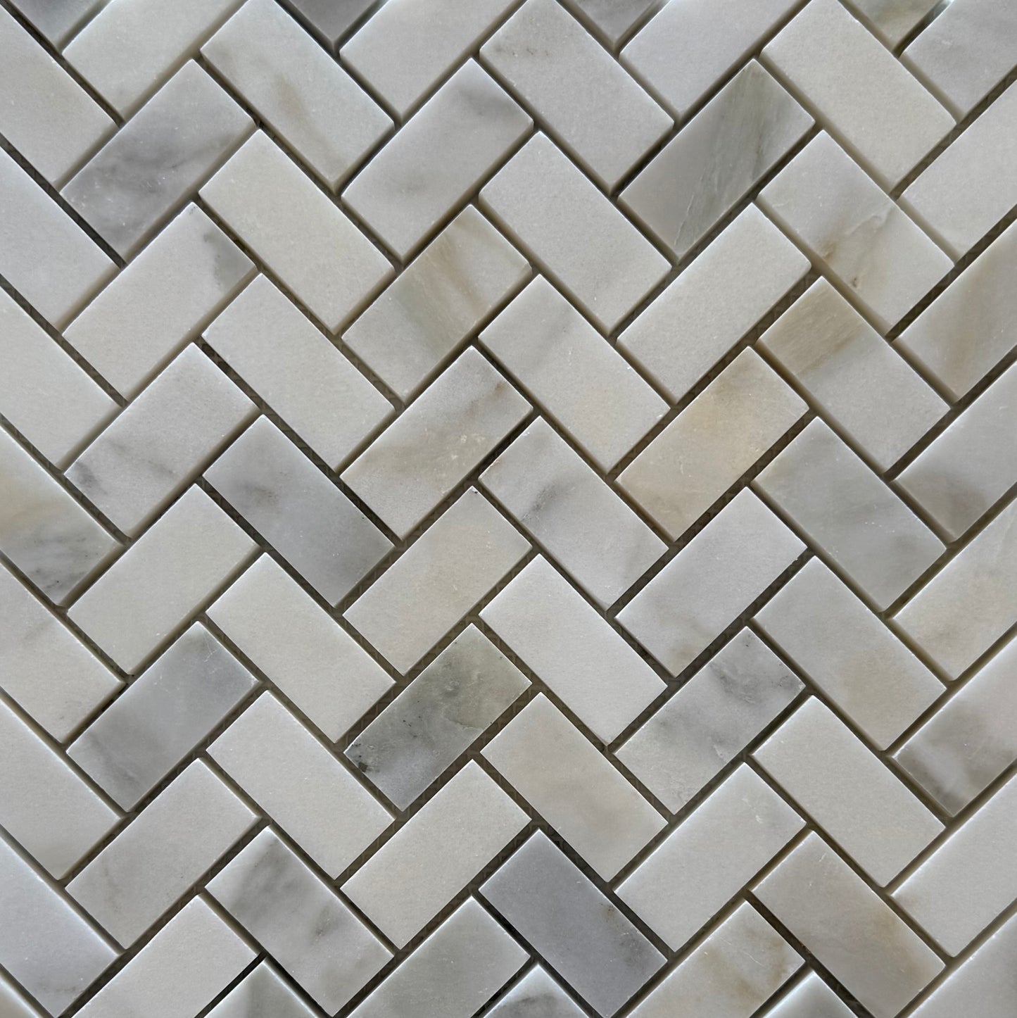 Close-up of a herringbone patterned tile with gray and white tones.