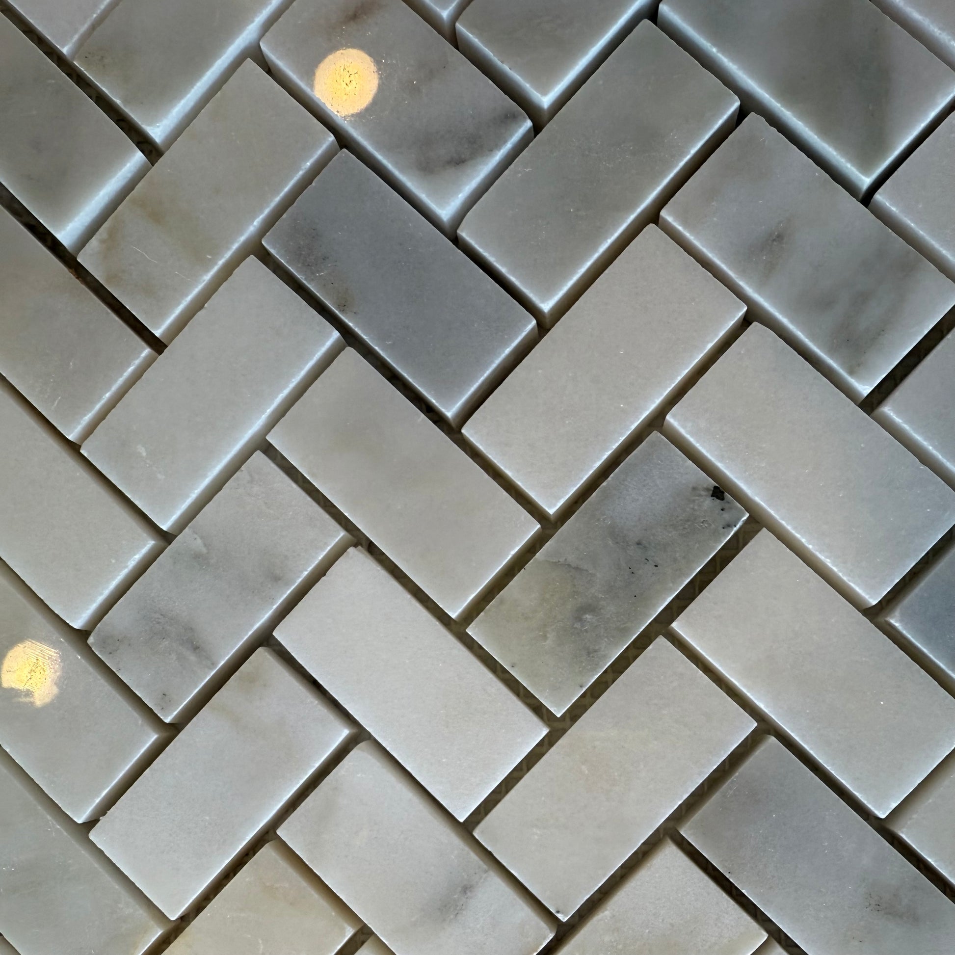 Gray marble tiles arranged in a herringbone pattern