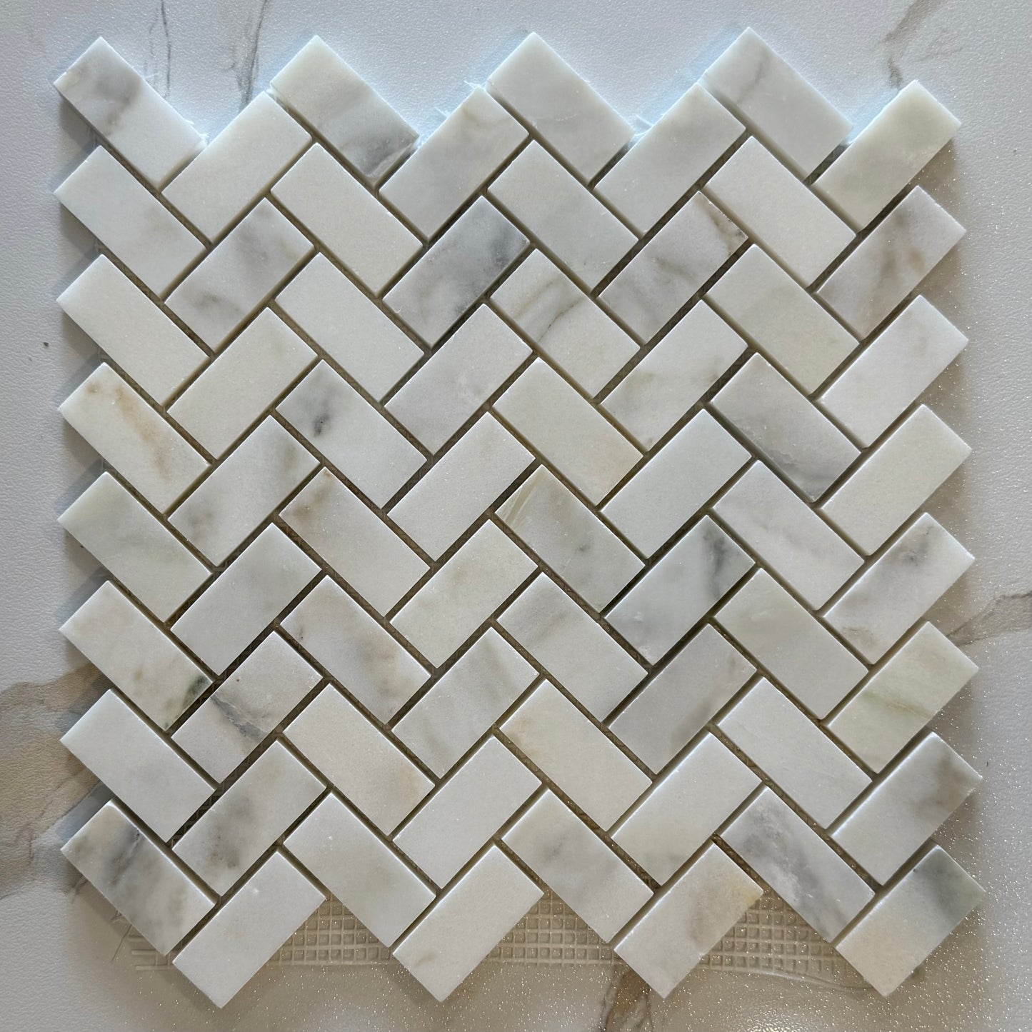 Marble mosaic tile with herringbone pattern on a light background
