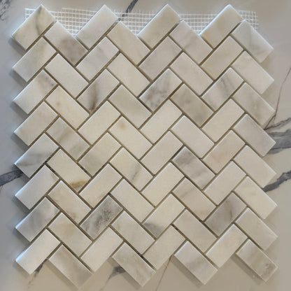 Marble mosaic tile sample with herringbone pattern on a white background