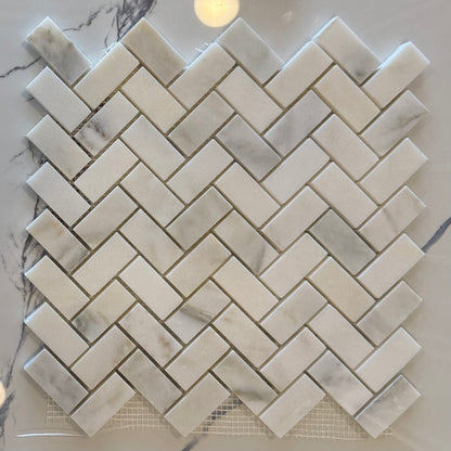 Marble mosaic tile sample with herringbone pattern on a marble surface