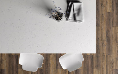 Top-down view of a modern kitchen with a white countertop, wooden floor, and white chairs.