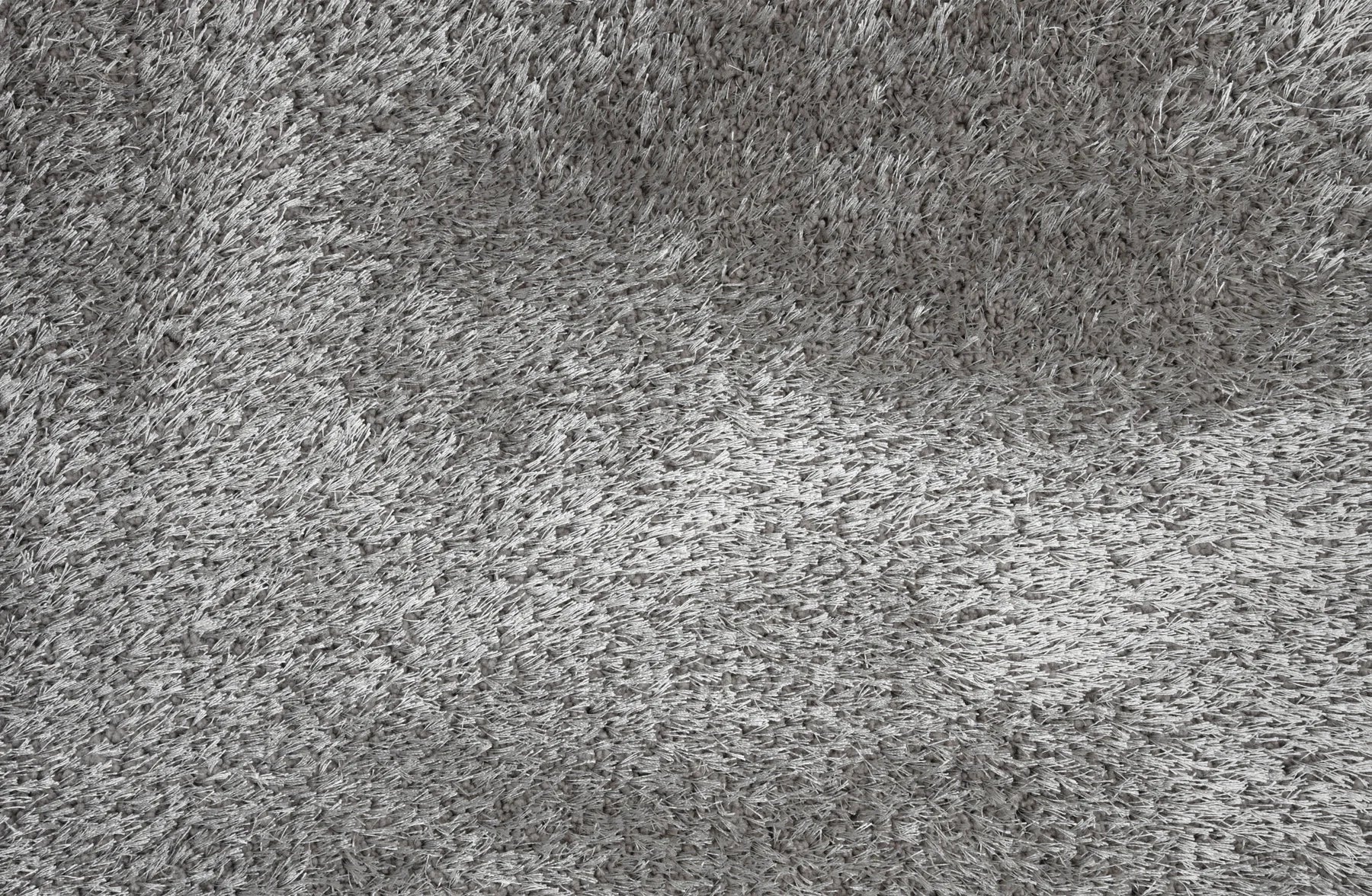 A close-up texture shot of a gray shaggy or high-pile carpet, showing the dense fibers and soft, fluffy surface.