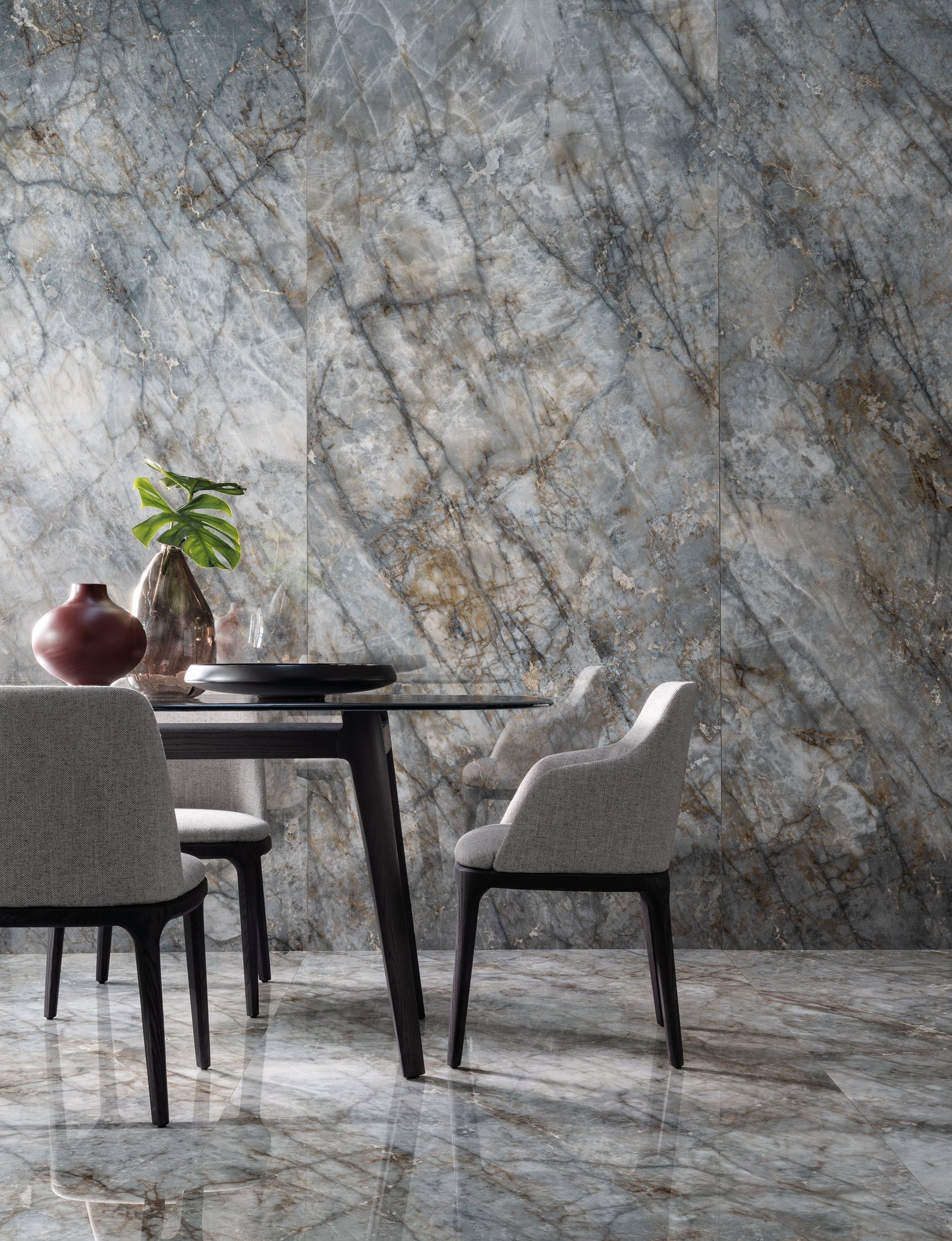 Dining area with marble table and chairs against a marble wall.