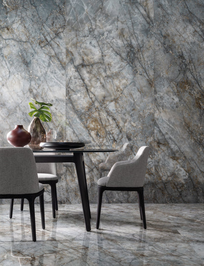Dining area with marble table and chairs against a marble wall.