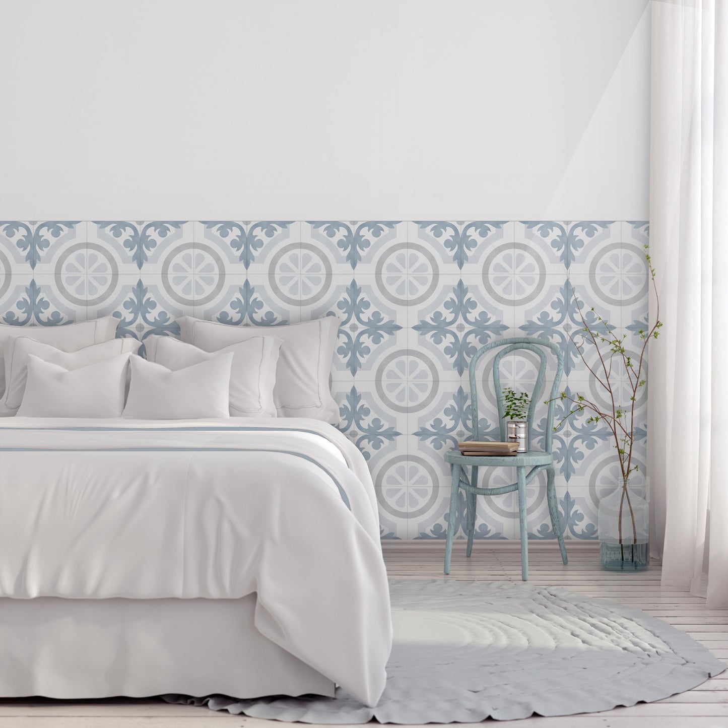 A styled bedroom scene featuring a decorative wallpaper with a blue and white geometric tile pattern on the lower half of the wall, paired with white bedding, a light blue vintage chair, and a white curtain.