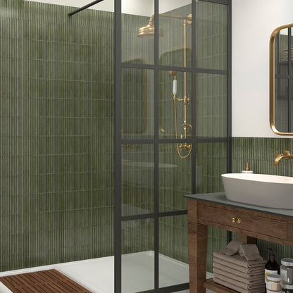 Modern bathroom with green tiled walls, glass shower enclosure, and wooden vanity.