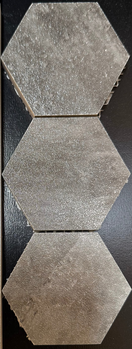 Three hexagonal tiles with a textured surface on a dark background