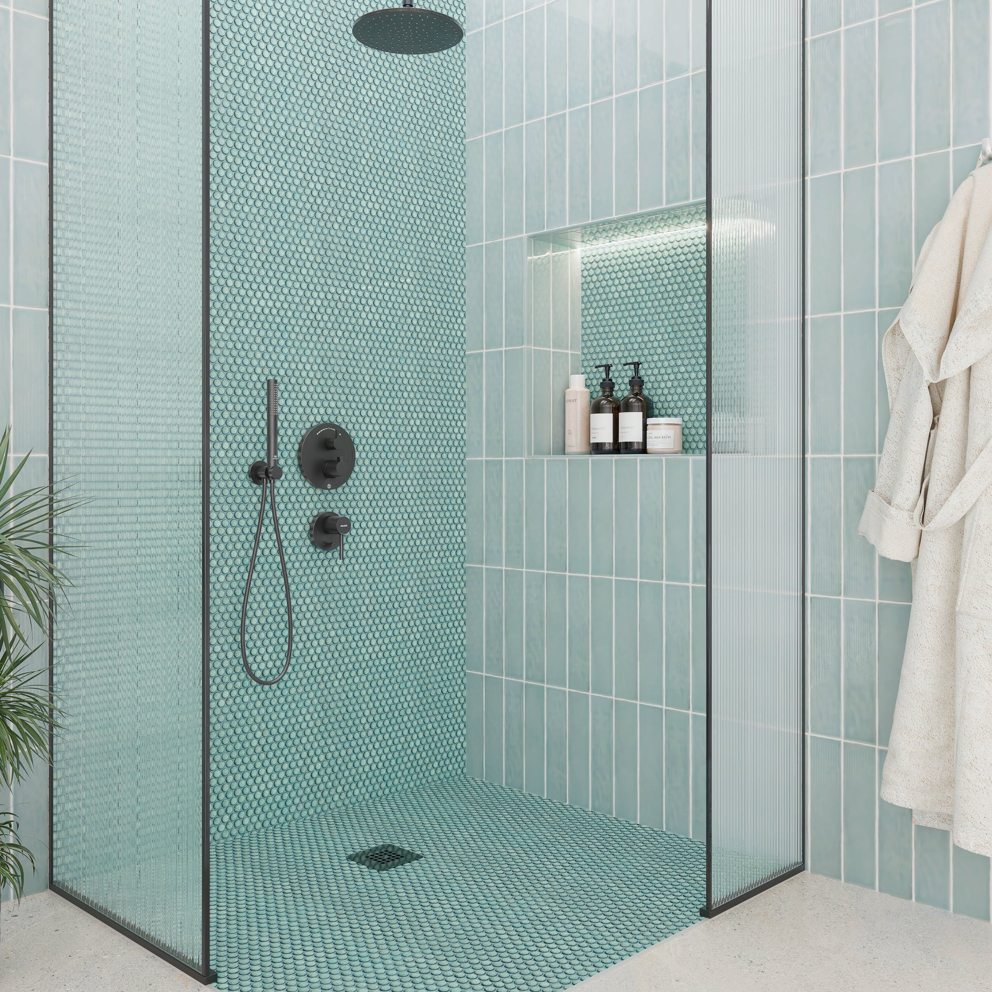 Modern bathroom with teal mosaic tiles, glass shower enclosure, and bathrobe.