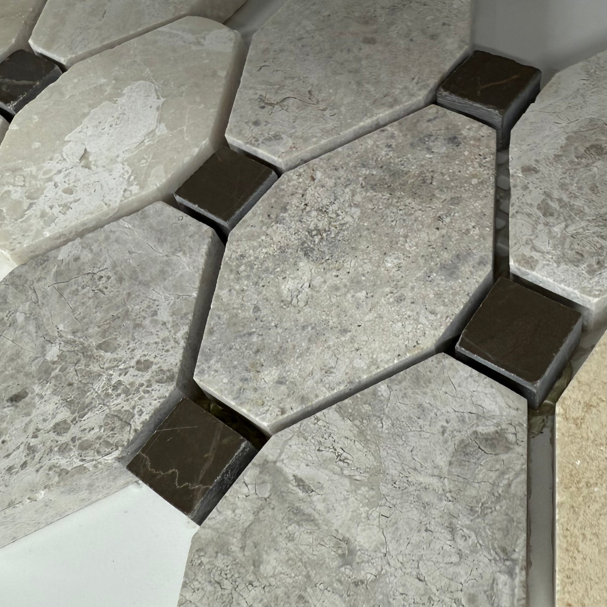 Hexagonal stone tiles with a mix of gray and brown colors on a tiled floor.