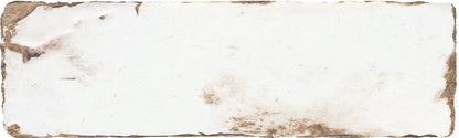 A square ceramic tile with a distressed, vintage-style off-white surface, featuring brown stained or aged markings along the rough, uneven edges.