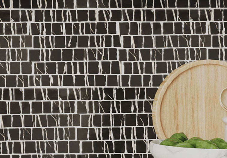 Black and white mosaic tile backsplash with a wooden cutting board and green apples.