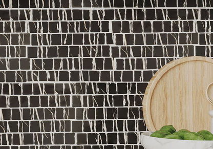 Black and white mosaic tile backsplash with a wooden cutting board and green apples.