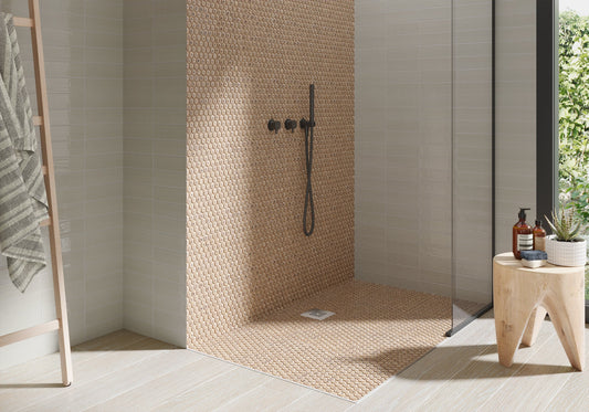 Modern shower with textured wall, shower head, and a small table with bottles.