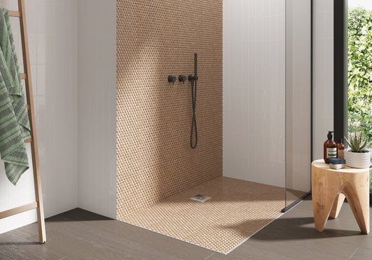 Modern shower with mosaic tile wall, wooden stool, and greenery outside.
