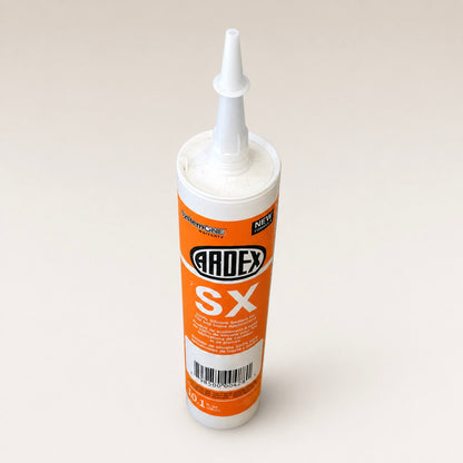 A tube of Ardex SX silicone sealant with an orange and white label, standing upright on a light beige background.