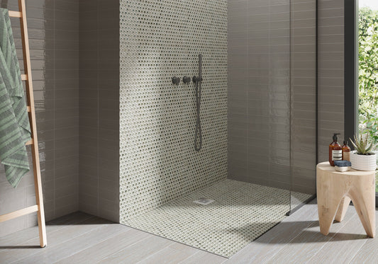 Modern shower area with mosaic tile wall and wooden stool.