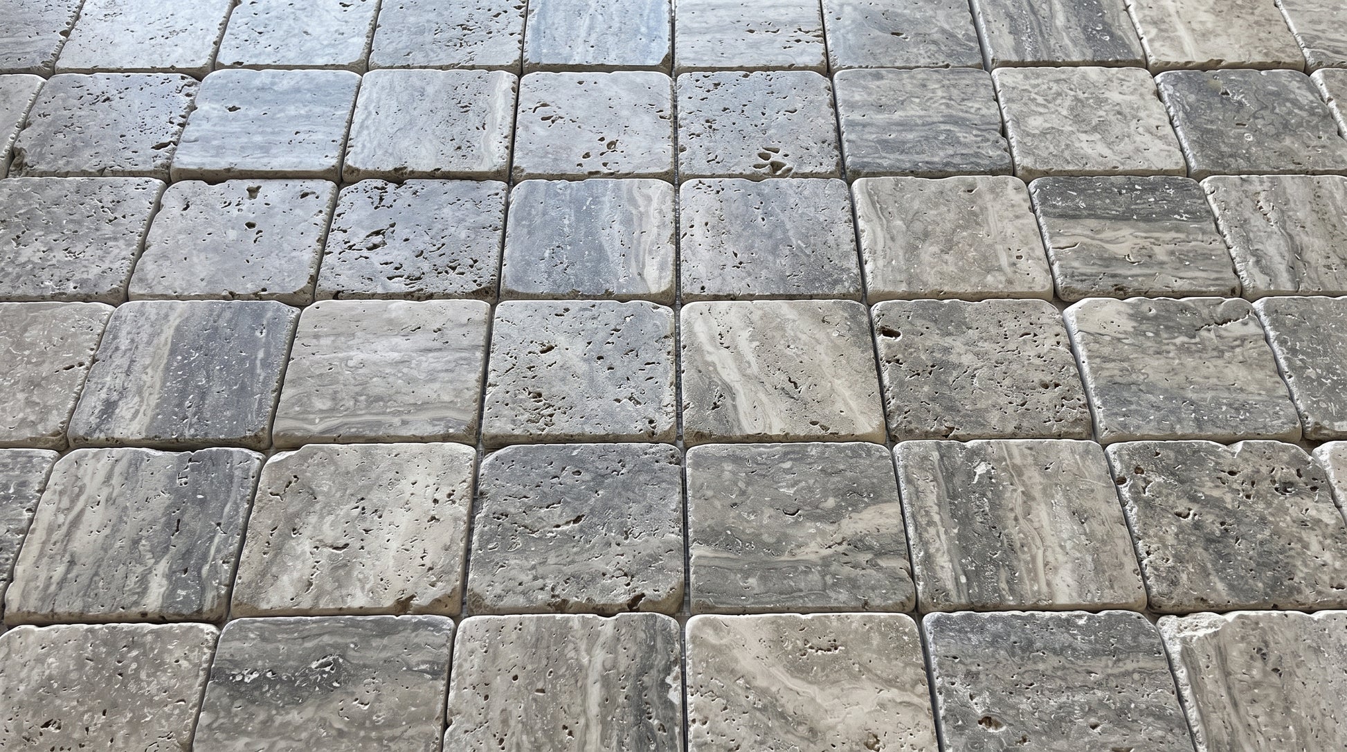 Gray stone pavers arranged in a grid pattern, showing natural stone textures and variations in color.