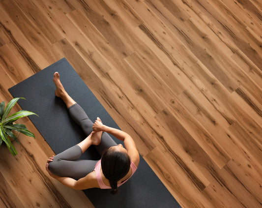 Person practicing yoga on a mat with a wooden floor background