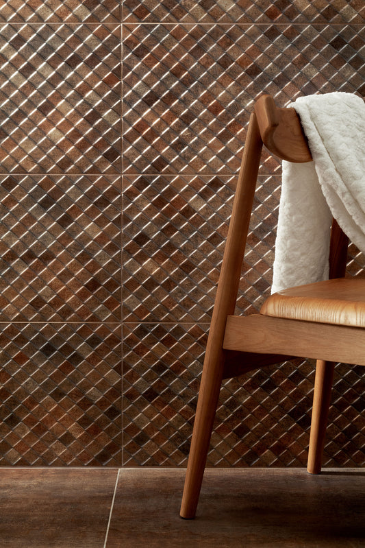 Brown mosaic diamond-patterned wall tiles with a wooden chair and white throw blanket in the foreground.