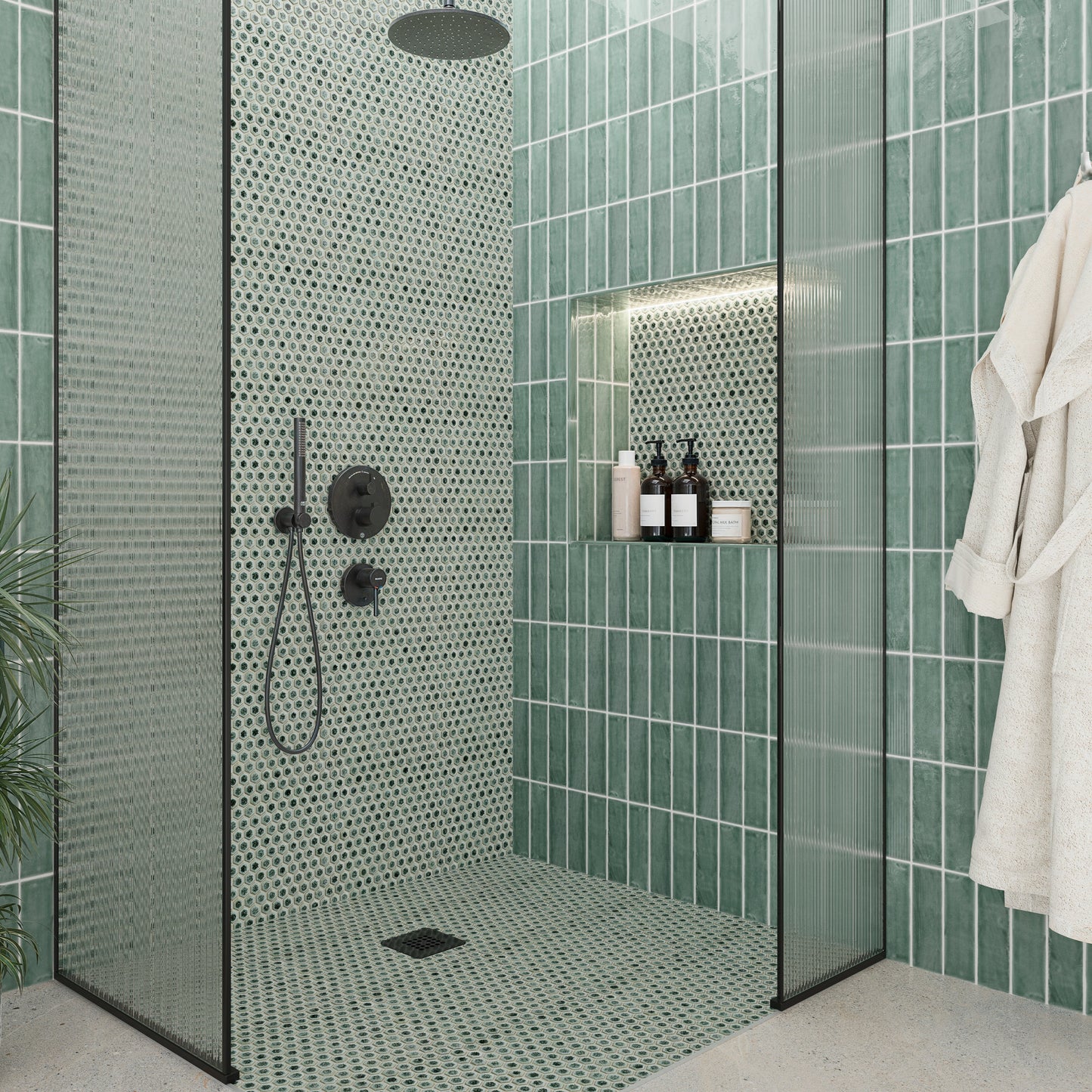 Modern bathroom with green tiled walls and a shower area.