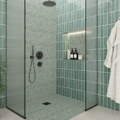 Modern bathroom with green tiled walls and a shower area.