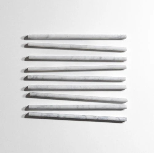 Seven long, slender rectangular bars with rounded ends, arranged in a staggered vertical row on a plain white background. The bars have a light gray to off-white color with subtle white veining, resembling marble or stone.