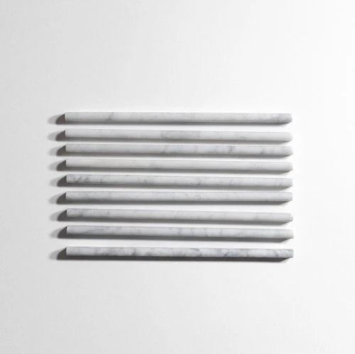 Seven long, narrow rectangular tiles with a white and light gray marble pattern, arranged horizontally in a row against a plain white background.