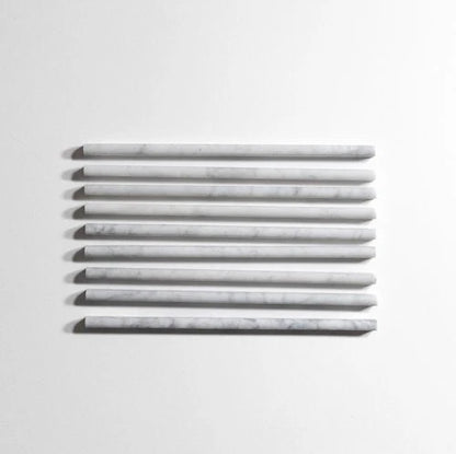 Seven long, narrow rectangular tiles with a white and light gray marble pattern, arranged horizontally in a row against a plain white background.