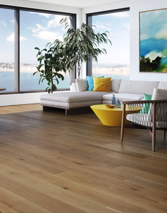 Modern living room with a sectional sofa, yellow coffee table, and large windows overlooking water.