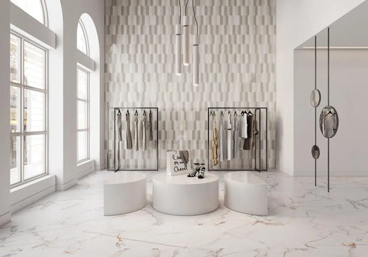 Modern interior with white marble flooring, round white tables, and clothing racks against a patterned wall.