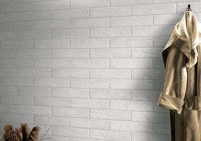 Beige bathrobe hanging on a hook against a gray tiled wall.